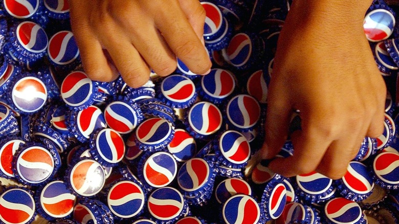 Hands riffling through Pepsi bottle caps 