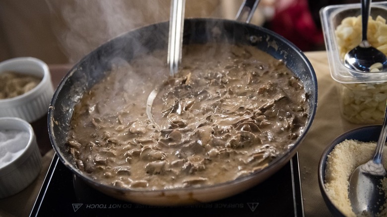 Steaming skillet of mushroom soup surrounded by ingredients