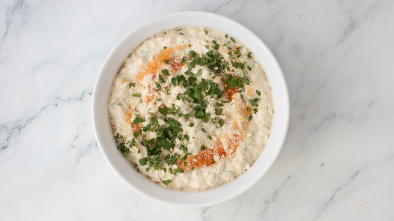 Creamy corn dip topped with sweet chili sauce, cilantro, and cotija