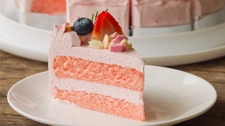 Layered cake with pink icing and fruit toppings
