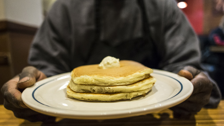 Person holding IHOP pancakes on plate