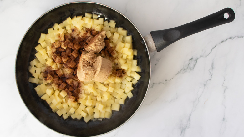 chopped apples, brown sugar, and spices in a black frying pan
