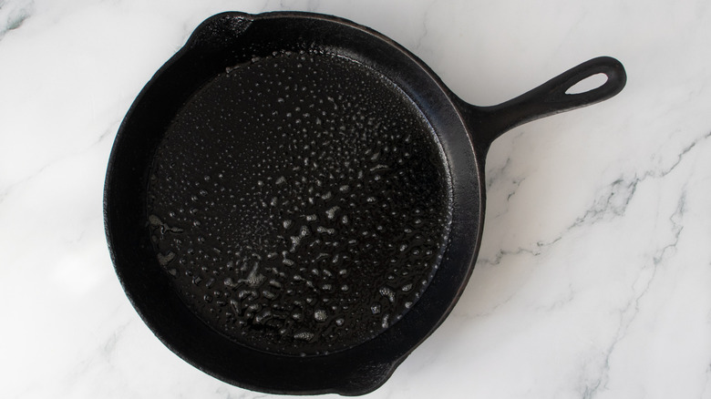 black frying pan with droplets of oil