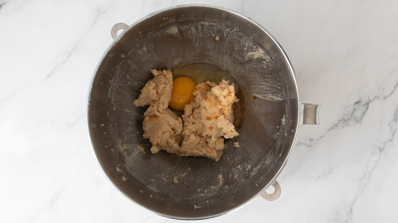 beige-colored butter and sugar mixture and raw egg in a metal bowl