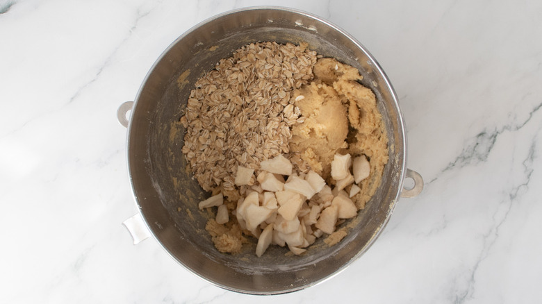 cookie dough, oats, and dried apples in a metal bowl