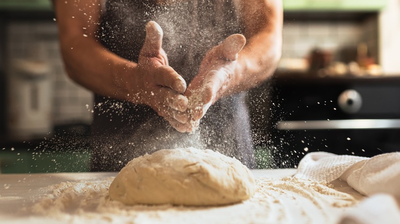 baker putting flour on dough