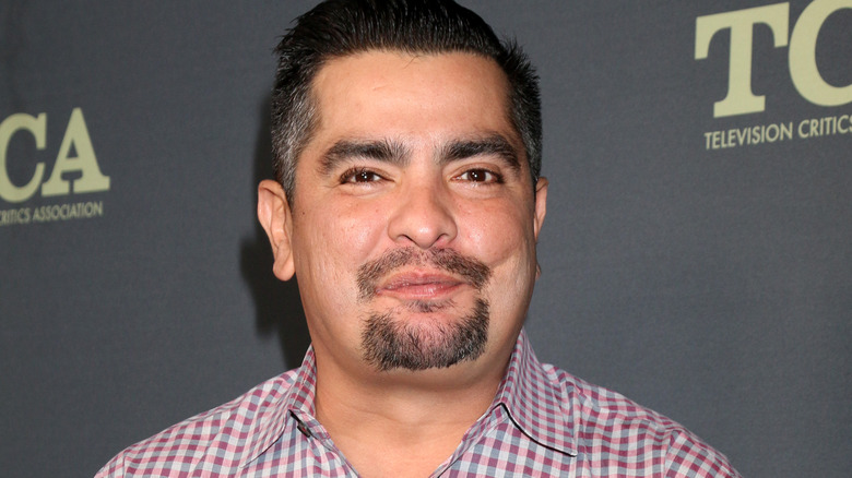 Chef Aarón Sánchez smiles in plaid shirt