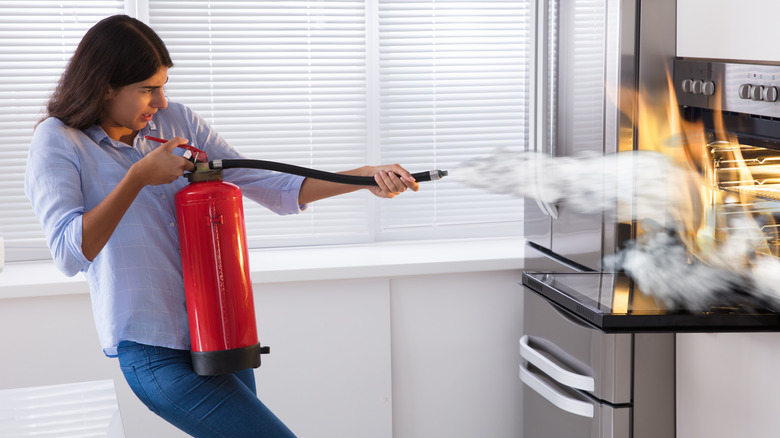 Woman using kitchen fire extinguisher