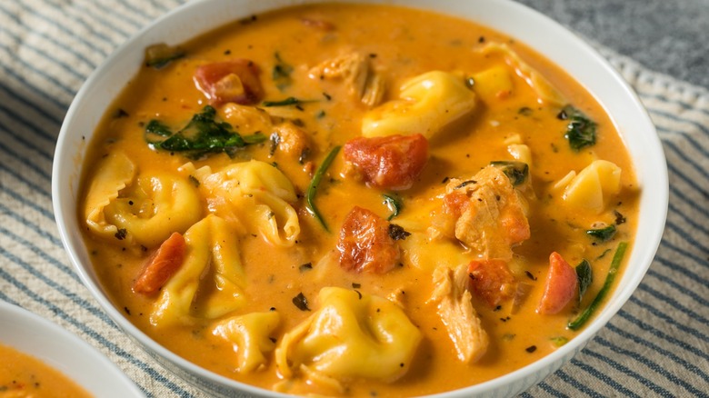 Soup with tortellini and tomatoes in a white bowl