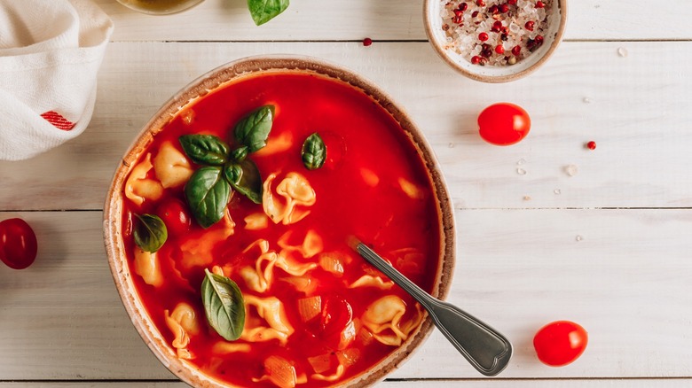 Tortellini in soup with a spoon and cherry tomatoes