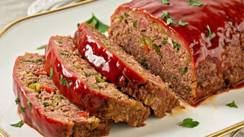 Red glaze-topped meatloaf with three slices cut on a plate