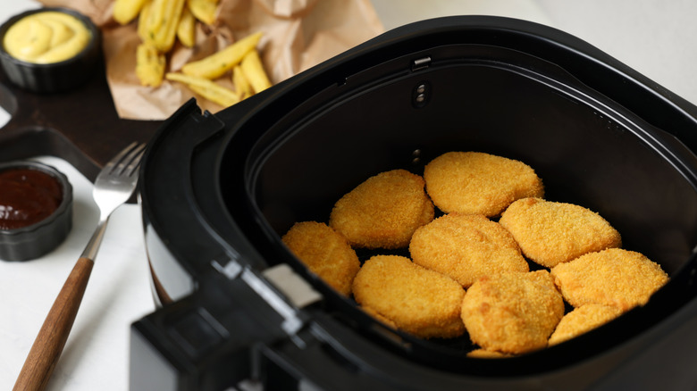 Chicken nuggets in air fryer basket.