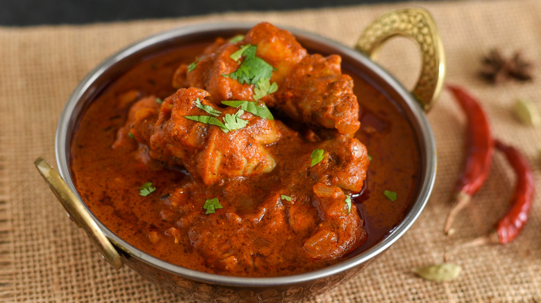 Chicken vindaloo in a tin bowl on a table 