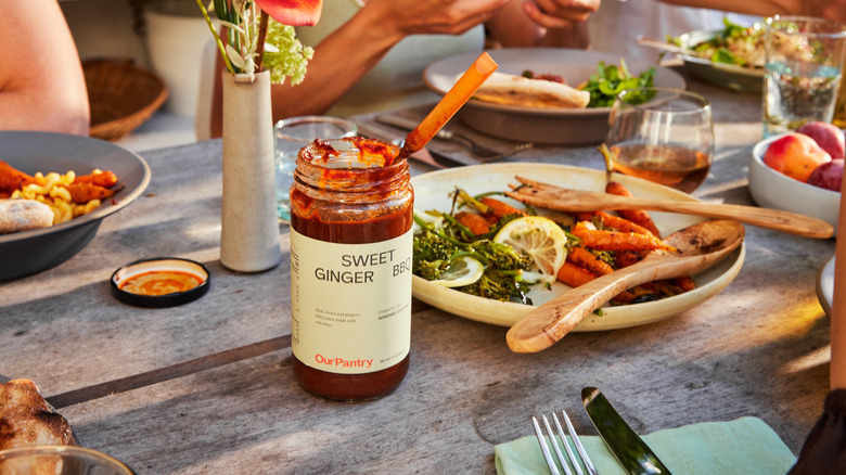 Jar of Sweet Ginger BBQ on table with food