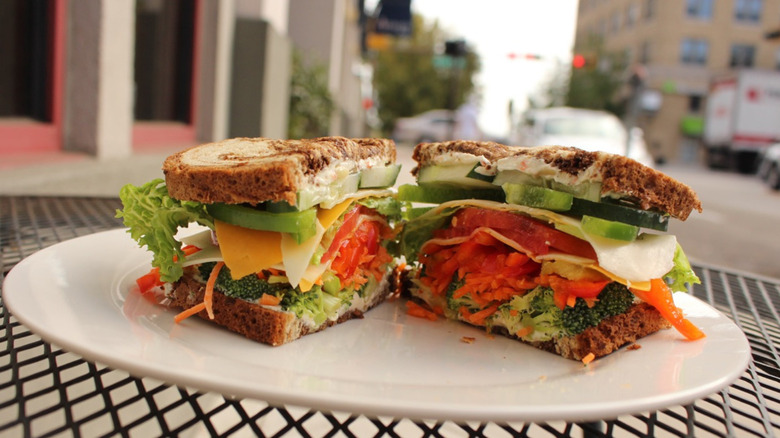 Veggie sandwich on white plate at outdoor table