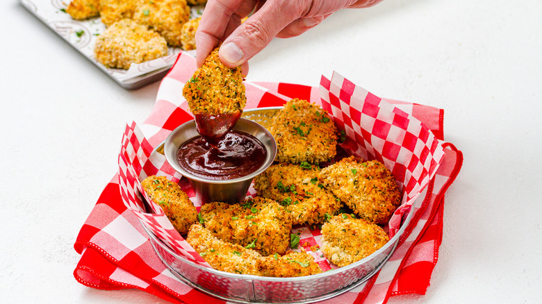 basket of homemade air fryer chicken nuggets with a small metal container of dipping sauce