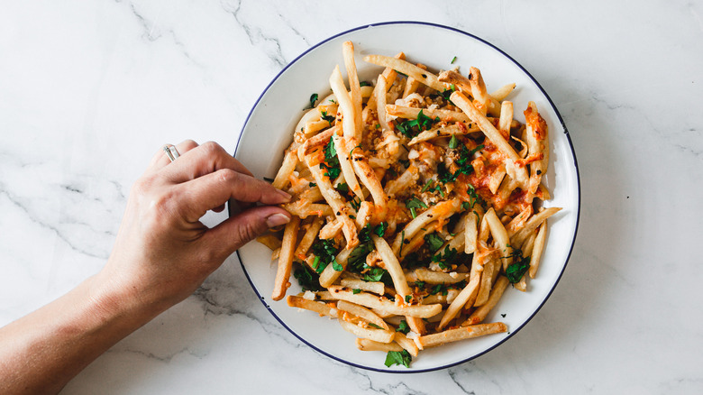 hand picking fry from plate