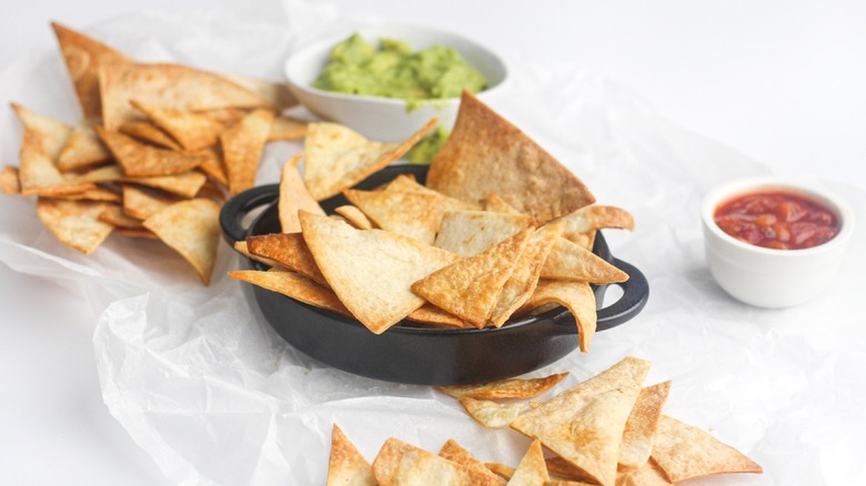 Air fryer tortilla chips with salsa and guacamole in separate bowls