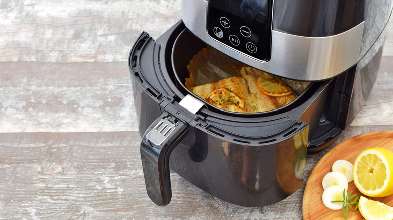 Air fryer basket partially open with fried fish inside