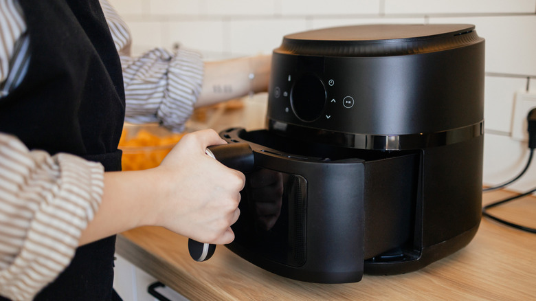 Woman pulling out the tray of an air fryer