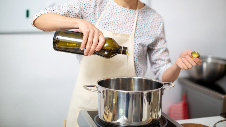 Woman pouring oil into a pot to fry fish
