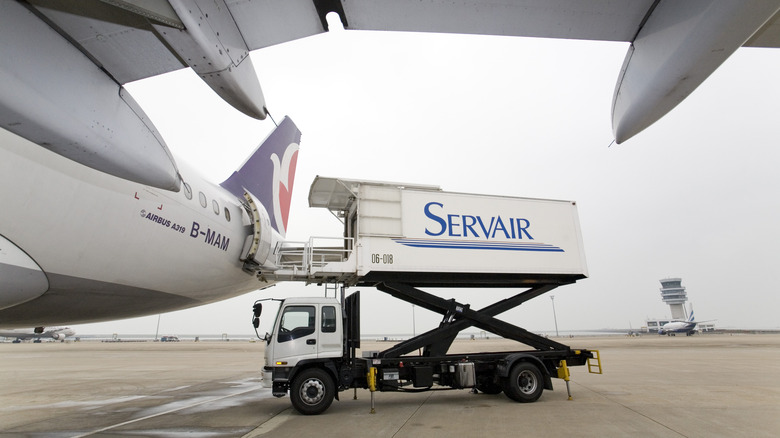 An airline catering truck delivers food to an airplane