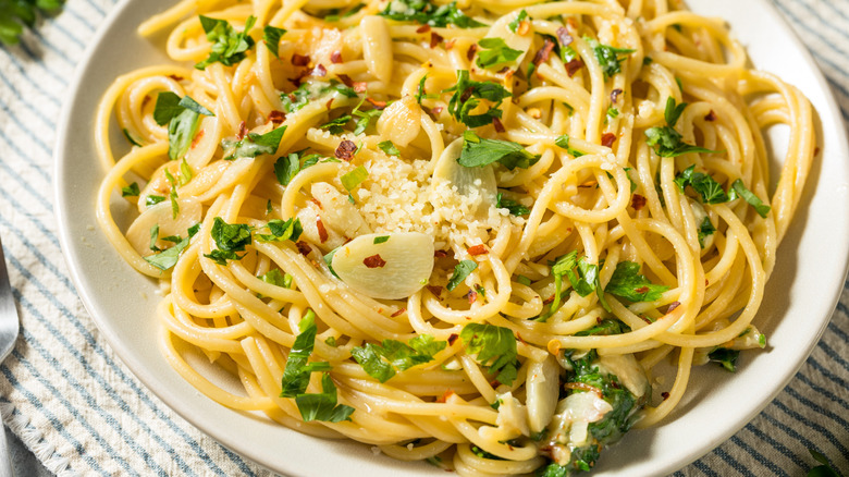 Closeup of white plate with spaghetti with garlic, parsley, chili flake