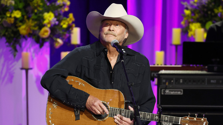 Alan Jackson holding guitar while performing on stage.