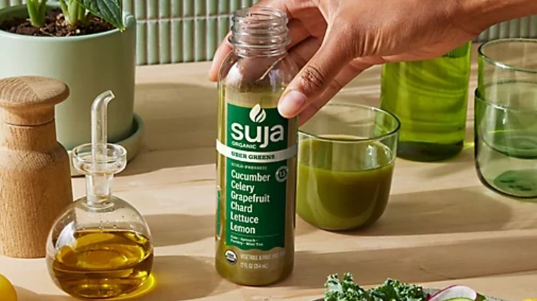 Hand touching Suja Organic Uber Greens Cold Pressed Juice on table