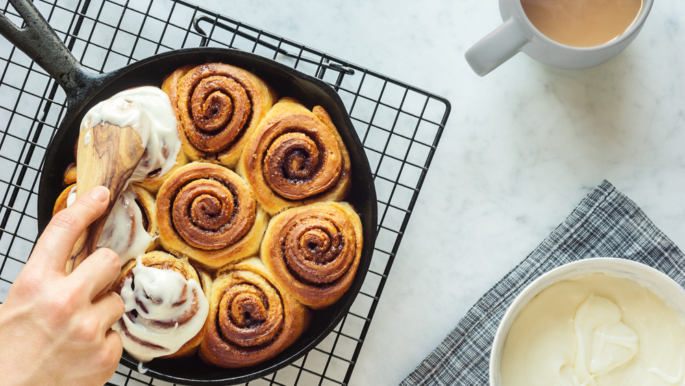 Woman icing a pan of cinnamon rolls