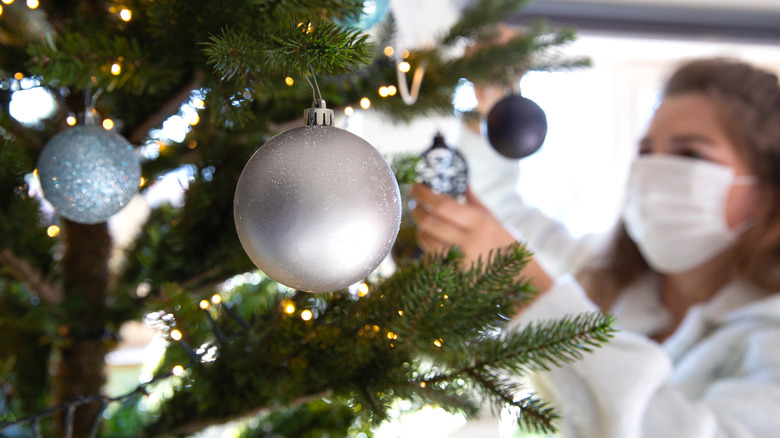 Person in white decorating a tree