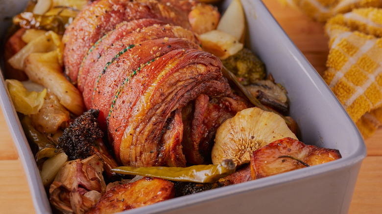 Rolled and roasted lamb breast with vegetables in pan