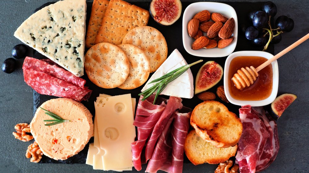 charcuterie board with cheeses, meats, almonds, fruit, and honey