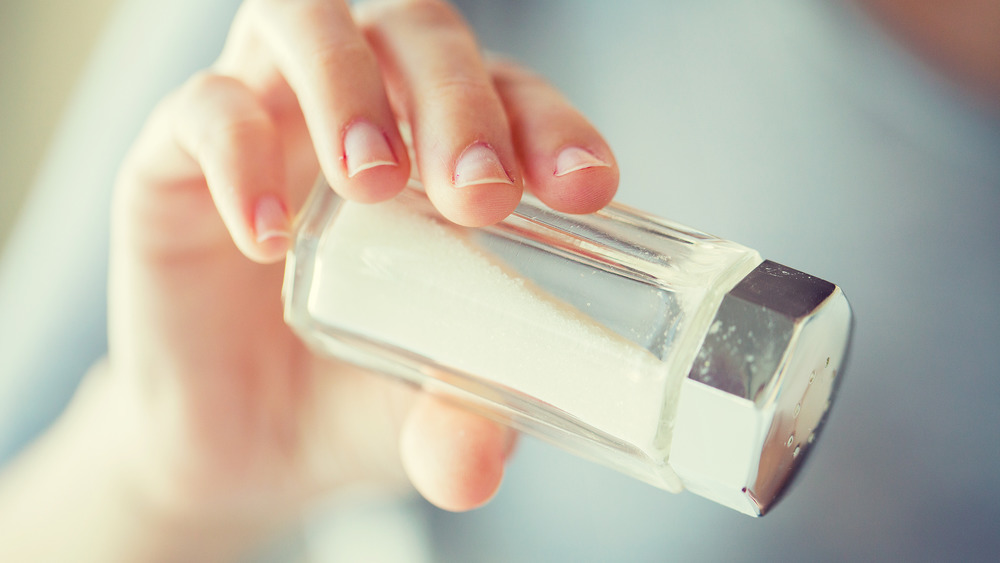 hand pouring salt shaker