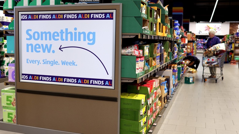 Endcap signage in an Aldi store with browsing customers in the background