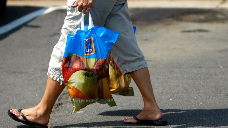 person holding Aldi grocery bag after shopping
