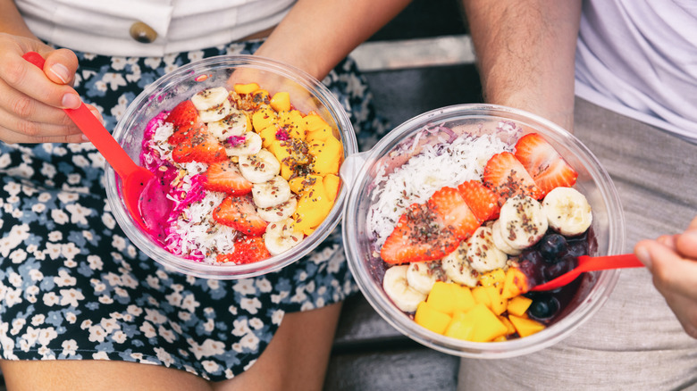 Two people eating açaí bowls