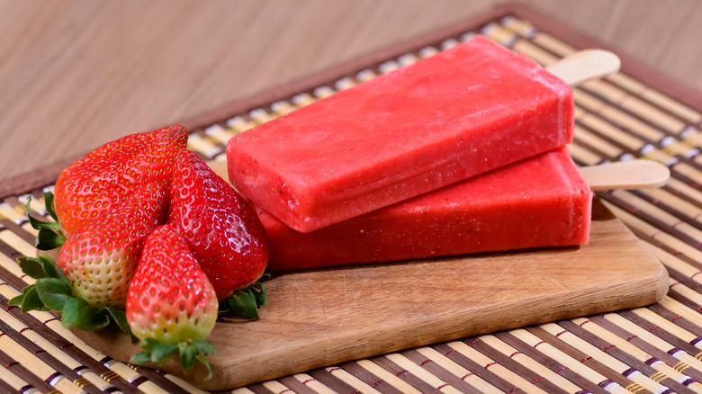 Frozen strawberry popsicle on table