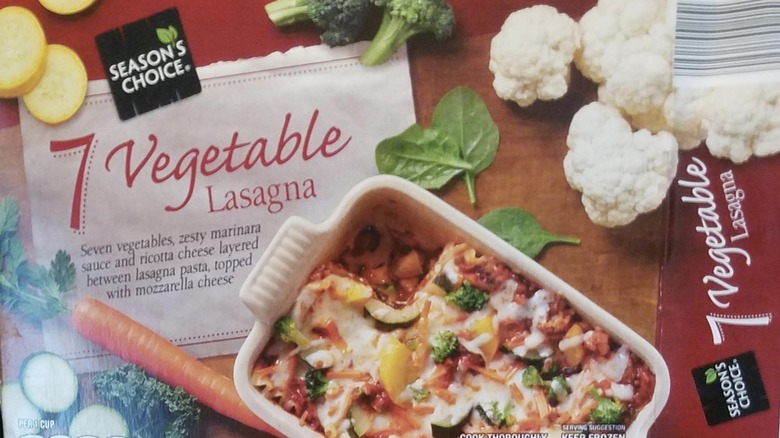 Person serving a portion of lasagna from a dish 