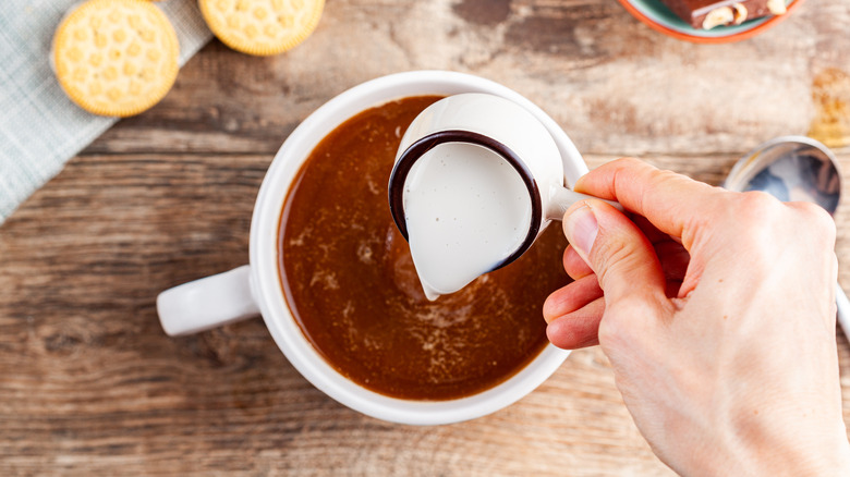 Creamer being added to a cup of coffee