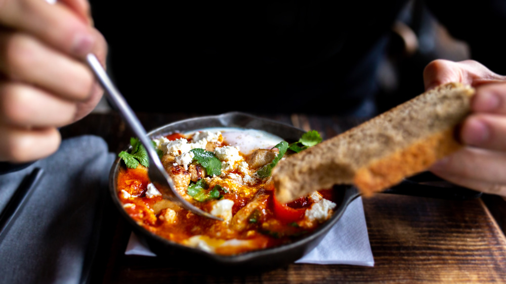 Man eating shakshuka with bread
