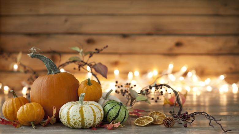fall themed decor with pumpkins, dried fruit, and string lights