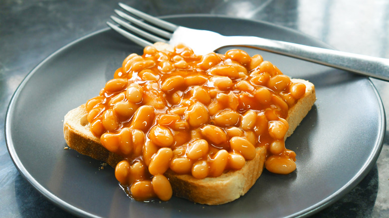 Beans on toast on dark plate with fork