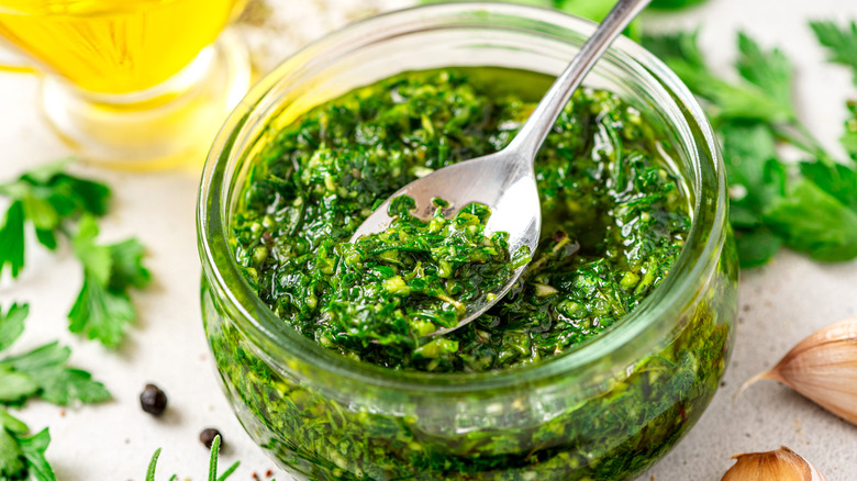 A spoonful and glass jar of fresh chimichurri sauce