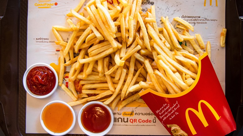 McDonald's french fries spilled on a tray with three dip cups