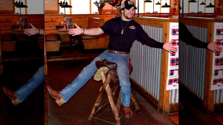 A Texas Roadhouse employee sitting on the birthday saddle smiling