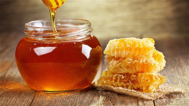 Raw honey combs next to glass container of honey