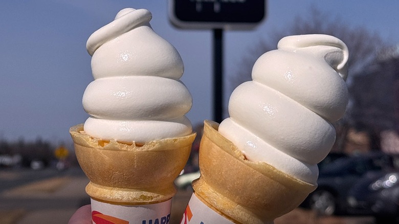 two ice cream cones held up outside