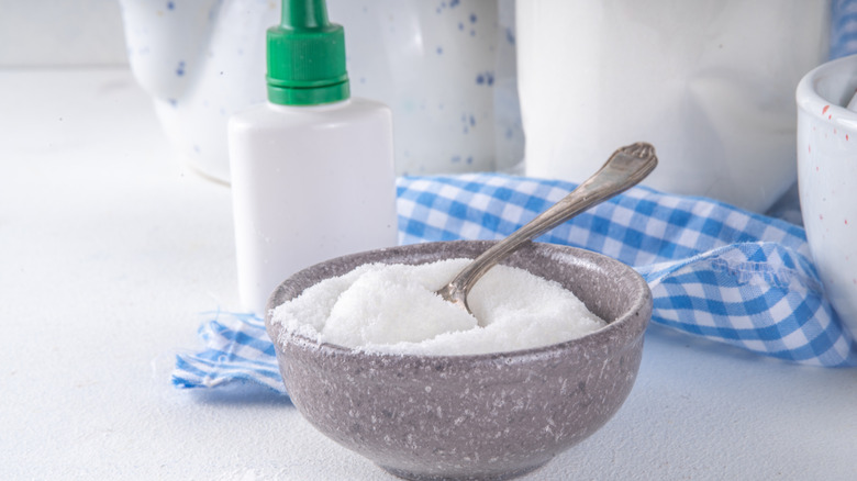 Allulose in a gray bowl with light blue checkered towel and white bottle in background