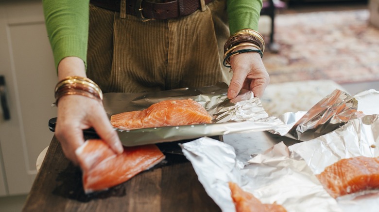 Person cooking salmon with aluminum foil